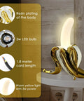 Banana Shaped Table Lamp With LED Night Light Modern Resin Banana Lighting Fixture on table, warm glow, resin plating, LED bulb shown.