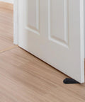 2Pcs Black Rubber Door Stopper Wedge With Antislip Surface for bedroom or office use shown under white door on wooden floor