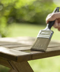 Applying Top Shelf Exterior Wood Stain For Outdoor Decks And Patios Waterproof Sealant With Superior UV Resistance 500 Ml Can on wooden table.