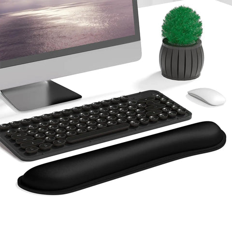 Cozy Memory Foam Keyboard Wrist Rest With Non Slip Base For Comfort And Pain Relief Ergonomic Mouse Pad Rest For Gaming Laptop And Computer Desk Use Cute Black placed in front of a desktop keyboard.