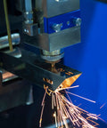 Industrial laser cutting machine sparks in a workshop.