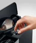 Hand adjusting the settings on the Top Tier Automatic Coffee Maker In Sleek Piano Black With One Touch Brewing.