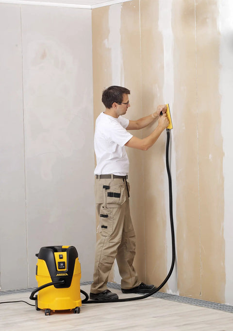 Person using vacuum hose for hand sanding blocks 13 ft lightweight flexible hose connected to industrial vacuum on wall