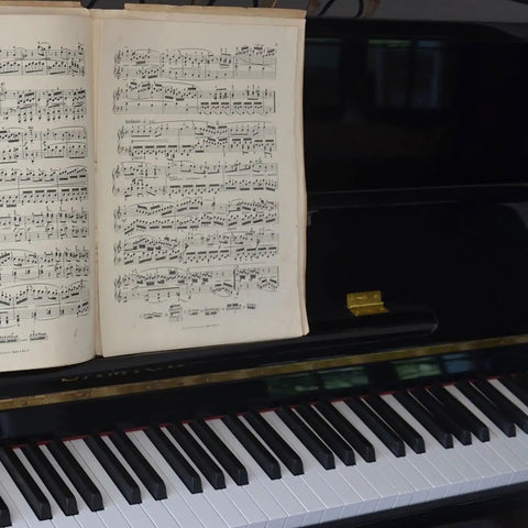 Open sheet music on a grand piano with a Copper Piano Hinges Set for Jewelry Boxes and Cabinets Four Smooth Quiet Folding Butt Hinges visible.