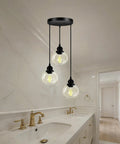 Three Light Pendant Light With Clear Glass Shades, Matte Black Finish hanging above a modern kitchen island