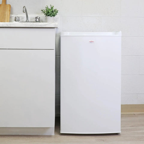 Hella Compact 3.1 Cubic Feet White Upright Freezer With Three Wire Baskets Garage Ready next to a sink in a kitchen setting.