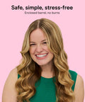 Smiling woman showing results of InfinitiPRO Curl Secret Ceramic Auto Curling Iron with soft curls, green top, pink background.