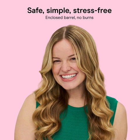 Smiling woman showing results of InfinitiPRO Curl Secret Ceramic Auto Curling Iron with soft curls, green top, pink background.