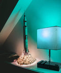 RGB Smart Table Lamp With Remote Control Alexa Voice And App Control Music Sync Dimmable Nightstand Lamp With Charging Station next to a rocket model on a shelf.