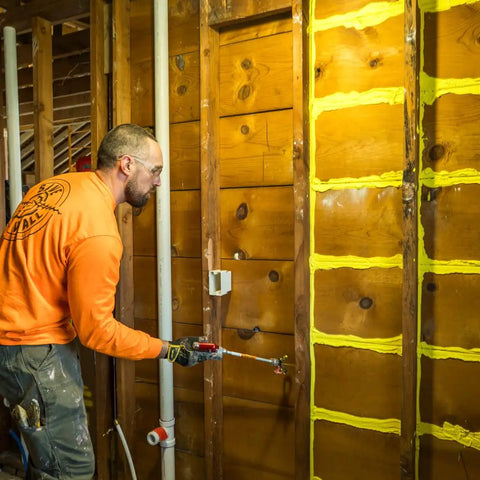 Professional Grade Interior Air Sealant Kicks Drafts To The Curb And Locks Warmth In Along Wall Ceiling Floor Joints Yellow 5 Gallon Big Bucket application on wall framing using caulking tool.