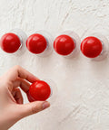 Hand applying Eight Pack Self Adhesive Red Round Cabinet Knobs Peel And Stick Handles for Glass Doors Refrigerators Cabinets