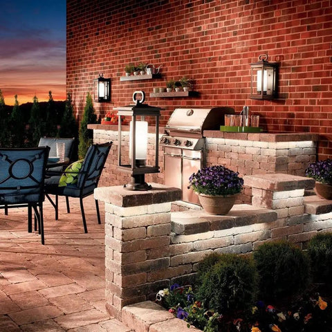 Outdoor patio with brick walls and South Hope 11.75 Inch Outdoor Wall Light Rubbed Bronze Sconce glowing on wall.