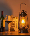 Pack Of 2 Vintage Rustic Lantern Lamps With Edison LED Bulbs, Bronze Rust Finish on a desk near wine and books