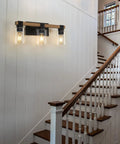 Farmhouse 3 Light Vanity Fixture With Rustic Wood And Clear Glass Shades for hallway, mounted on white paneled wall.