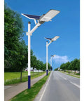 Hella Bright 200 Watt Solar Outdoor Flood Lights With Remote Control And Dusk To Dawn Sensor IP65 Waterproof Garden Yard Lamps For Fence Pathway Zero Hassle Install mounted along a tree-lined road.