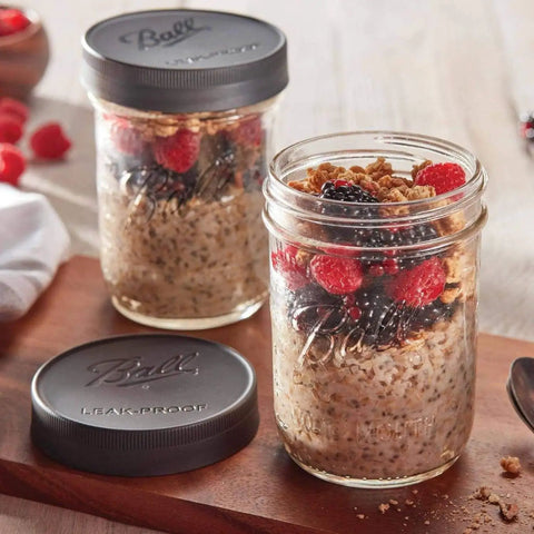 Two Mason jars with oatmeal and berries, one open lid. Leak-Proof Wide Mouth Mason Jar Lids, 6 Pack, Durable Seal Keeps Food Fresh And Spill-Free.