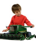 Child playing with John Deere T670i 1 To 16 Scale Combine Harvester Toy, designed for indoor and outdoor play, German-made with ABS plastic.