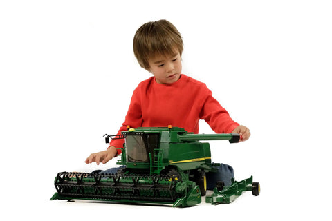 Child playing with John Deere T670i 1 To 16 Scale Combine Harvester Toy, designed for indoor and outdoor play, German-made with ABS plastic.