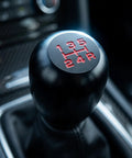 Upgrade Your Ride With This Sleek Kisa Angel 2 Piece Weighted Shift Knob Set For Manual Cars Featuring Ergonomic Grip, Anodized Finish, And Universal 8 10 12 Mm Adapter Kit For Smooth Gearing Action. black aluminum 5-speed manual shift knob close-up in car