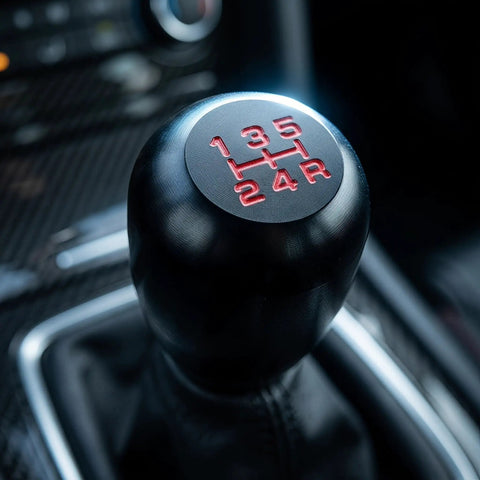 Upgrade Your Ride With This Sleek Kisa Angel 2 Piece Weighted Shift Knob Set For Manual Cars Featuring Ergonomic Grip, Anodized Finish, And Universal 8 10 12 Mm Adapter Kit For Smooth Gearing Action. black aluminum 5-speed manual shift knob close-up in car