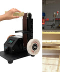 Hand using wood on 96 Watt 7 Speed Mini Belt Sander Bench Grinder And Polisher featuring dual coarse fine wheels.