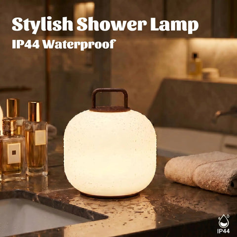 Cordless RGBW LED Table Lamp With Remote Control on a bathroom counter, IP44 waterproof for shower use, glowing softly.