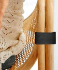 Person sitting on wicker chair with black clip; 4 Pack Outdoor Furniture Clips For Wicker Sectional Sofas And Rattan Chairs Black 90mm Inner Diameter Easy Clip Fasteners For Seamless Sectional Alignment And No Fuss Outdoor Lounge Sets