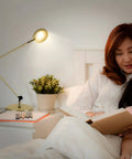Sage 2 In 1 LED Craft Table And Floor Lamp in gold finish illuminating a mother reading to her child in a cozy bedroom setup.