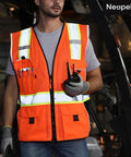 Heavy Duty Ansi Reflective Safety Vest In Bright Orange Mesh With Multi Function Pockets And 3M Retroreflective Tape worn by man holding radio.