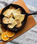 10 Inch Preseasoned Cast Iron Skillet With Ergonomic Handles, Pour Spouts, and crepes on a cutting board