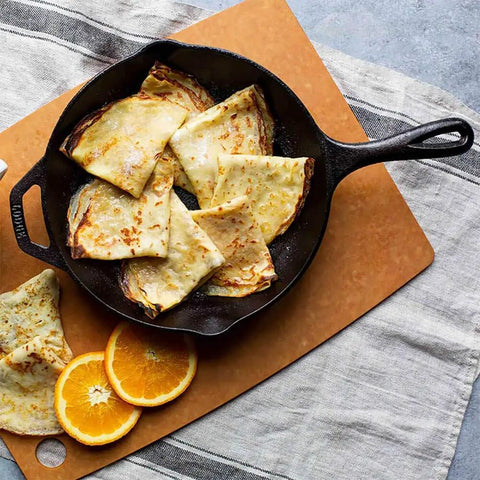 10 Inch Preseasoned Cast Iron Skillet With Ergonomic Handles, Pour Spouts, and crepes on a cutting board