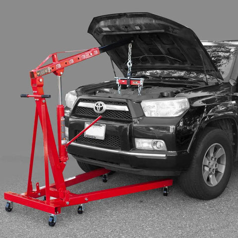 Top Shelf 2 Ton Steel Garage Engine Hoist With Folding Frame And Hydraulic Long Ram Jack positioned over a black vehicle's engine.