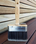 Go To Rapid Stain Deck Brush Applicator 5 Inch with wooden handle placed on wooden deck surface for staining and sealing.