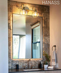 Gold Finish 15 Inch Two Light Vanity Light With Clear Globe Glass Shades over bathroom mirror on stone wall