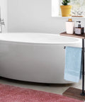 Dark Brown Toilet Paper Holder Stand For Bathroom with shelf, towel, and decor beside white bathtub in bright setting.