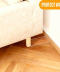 Clear Acrylic Couch Wall Spacer And Bed Blocker Stops Furniture Scrapes Keeps Heaters Cool Preserves Outlet Access Built Tough No Sweat Setup Invisible Wall Guard Anti Scratch Two Pack under couch leg on wooden floor.