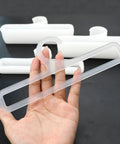 Hand holding one of the Set Of 50 White Plastic Hangers For Retail Display And Home Closet Organization, showing size and design.