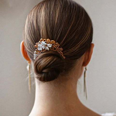 Woman with hair bun adorned with decorative hairpin featuring floral and silver details, viewed from behind.