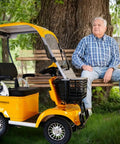 Legit 60V Electric Mobility Scooter Built Tough With A Beefy 650 Watt Motor parked beside a man on a bench in a park.