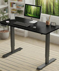 Rock Solid 55 Inch Electric Standing Desk With Double Beam Frame for Home Office or Gaming Setup in black with keyboard and monitor.