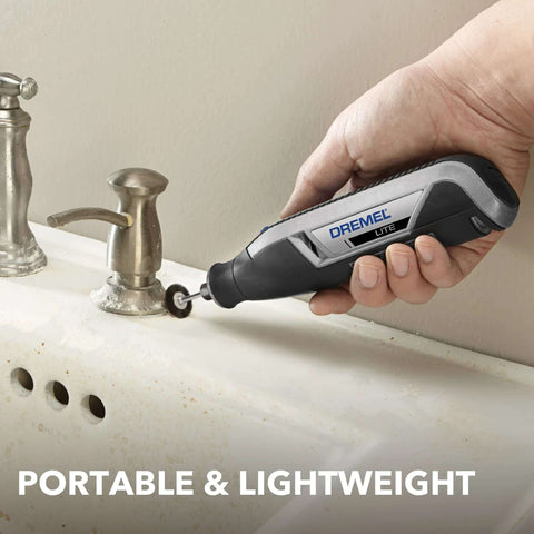 Dremel Lite cordless rotary tool held in hand beside a sink, gray/black body with a small grinding wheel attached.