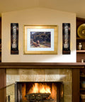 Antique bronze wall sconces featuring openwork glass shade tealight holders mounted beside a framed painting for cozy ambiance.