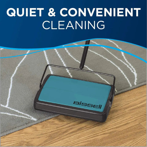 Super Lightweight Cordless Floor Sweeper With Dual Bottom Dump Bins For Snap Up Messes And Dust Clumps On Hardwood Tile And Area Rugs Compact Push Broom Cleaner In Teal on a gray area rug.