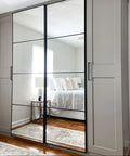 Bedroom wardrobe with mirrored doors reflecting a bed and side table, showcasing All In One Refinishing Paint For Furniture And Cabinets No Stripping No Sanding No Priming Needed Pebble Color Quart Easy To Apply With A Pro Finish For DIY Home Makeovers.