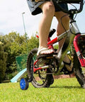 Child on bike with Bicycle Training Wheel Kit With Heavy Duty Support Bracket And Adjustable Wheel Design for home practice.