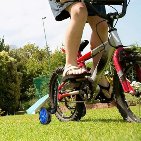 Child on bike with Bicycle Training Wheel Kit With Heavy Duty Support Bracket And Adjustable Wheel Design for home practice.