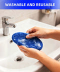 Blue microfiber windshield cleaning pad being held with soap suds over a bathroom sink