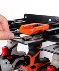 Close-up of wall mounted drill storage rack for four drills and accessories, keeps cords tidy with anti slip dish trays