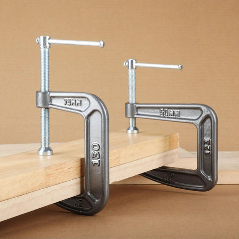 Heavy Duty C Clamp For Home, Garage, And Shop Use, Steel Construction gripping wooden boards on a workbench for woodworking projects.