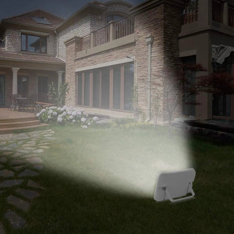 JUDYSSY Solar Floodlight Outdoor with 180° Angle Lighting Adjustable showing bright light on grass by a house.